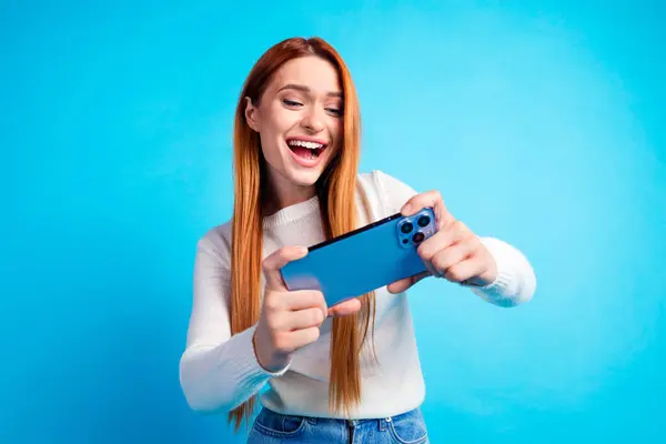 stock image Photo portrait of attractive young woman play mobile game have fun dressed stylish white clothes isolated on blue color background.