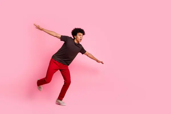 全身上下都是光怪陆离的家伙单腿站在空中试图用粉色背景隔离的双手保持身体平衡的照片 — 图库照片