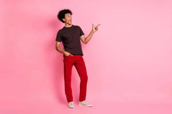 全长身体照片滑稽快乐的男人穿着鲜艳的衣服直指广告牌有趣地宣布孤立在粉红的背景下 — 图库照片