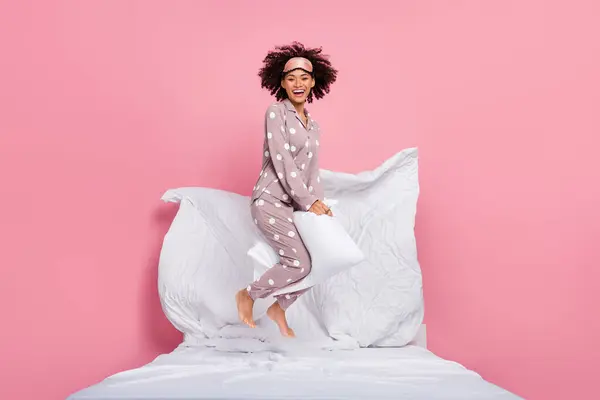 Photo of cheerful funky lady wear pajama smiling riding pillow jumping high isolated pink color background.