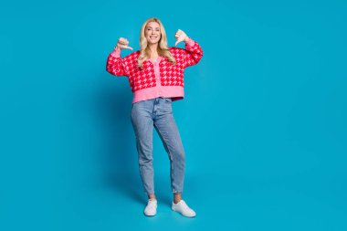 Full size photo of assertive confident person dressed knitwear jumper jeans indicating at herself isolated on blue color background. clipart