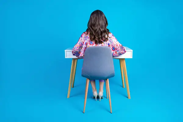 身材匀称的老妇人坐在餐桌后面 穿着时髦 五彩缤纷的衣服 背景为蓝色 — 图库照片