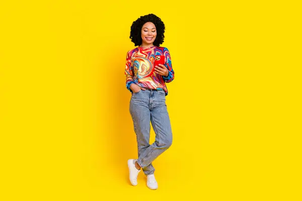 Stock image Full body portrait of nice young woman use smart phone empty space wear pullover isolated on yellow color background.