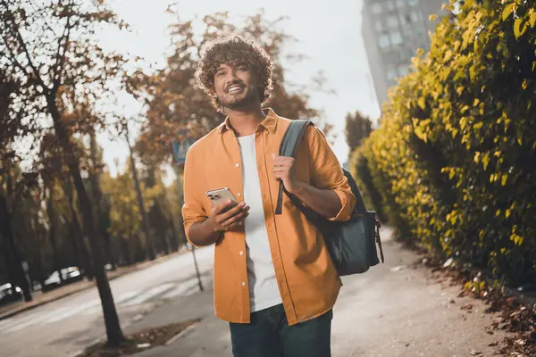 Photo of positive cheerful arabian man tourist enjoying vacation walking going outside urban city street.