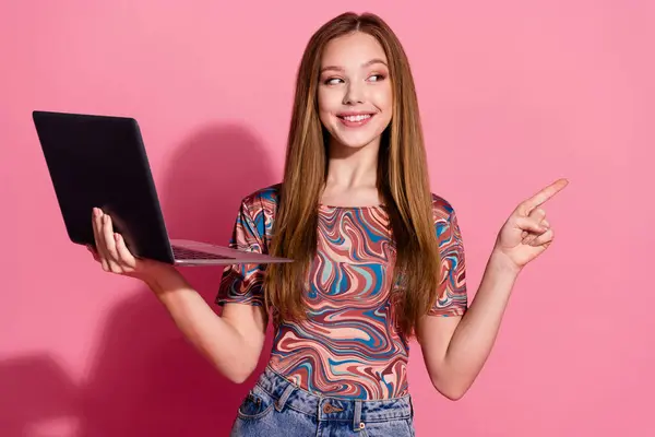 穿着五颜六色衬衫的漂亮青少年的画像手持着笔记本电脑 直奔出售用粉色背景隔开的空旷空间 — 图库照片