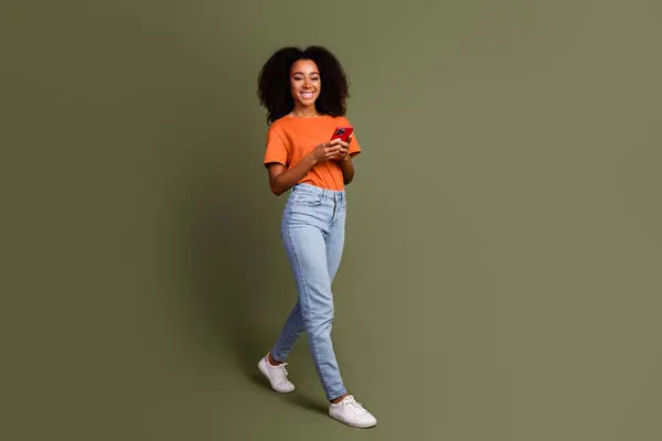 stock image Full length photo of shiny attractive lady dressed orange outfit texting modern device empty space isolated khaki color background.