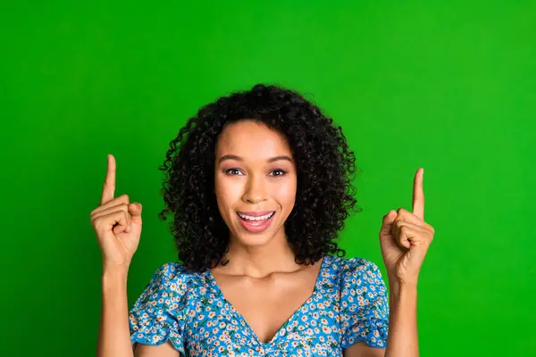 Photo of nice young woman direct fingers up empty space wear top isolated on green color background.