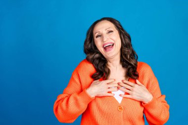 Photo portrait of gorgeous senior woman touch chest laughing wear trendy orange outfit hairdo isolated on blue color background. clipart