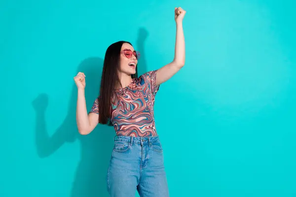 stock image Photo of lucky attractive lady dressed print top pink glasses rising fists empty space isolated teal color background.