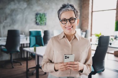 Photo of attractive good mood age lady agent dressed formal shirt texting sms modern gadget indoors workplace workstation loft. clipart