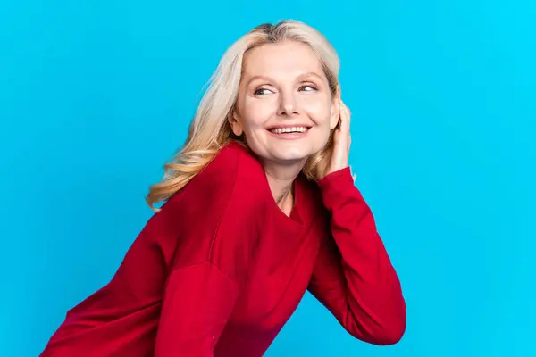 stock image Photo portrait of pretty senior female look empty space tuck hair behind ear wear trendy red outfit isolated on blue color background.