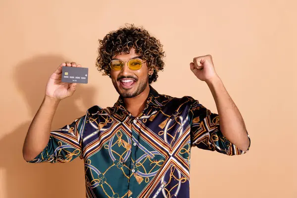 stock image Photo portrait of pretty young guy hold credit card winning wear trendy print outfit isolated on beige color background.