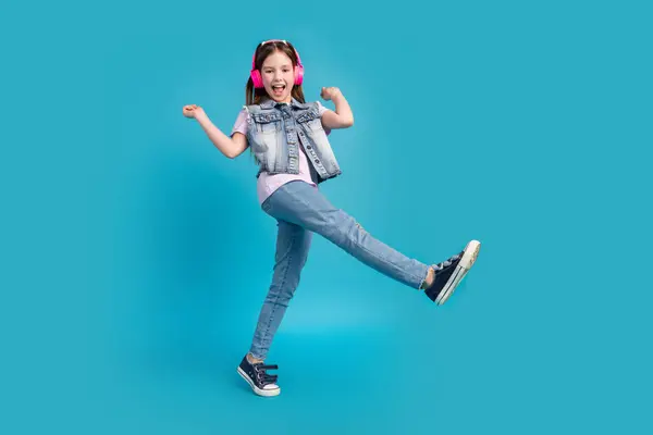 stock image Full size photo of charming little girl earphones dance have fun wear trendy jeans outfit isolated on blue color background.