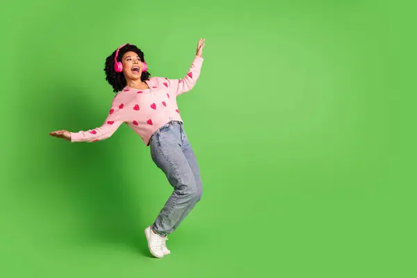 stock image Full length photo of lovely young lady headphones tiptoes dancing dressed strawberry print pink garment isolated on green color background.