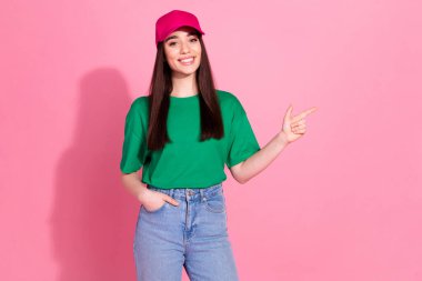 Photo of shiny attractive lady dressed green t-shirt pink headwear pointing empty space isolated pink color background. clipart