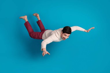 Full size photo of nice young male flying have fun wear nightwear sleepover good night isolated on blue color background. clipart