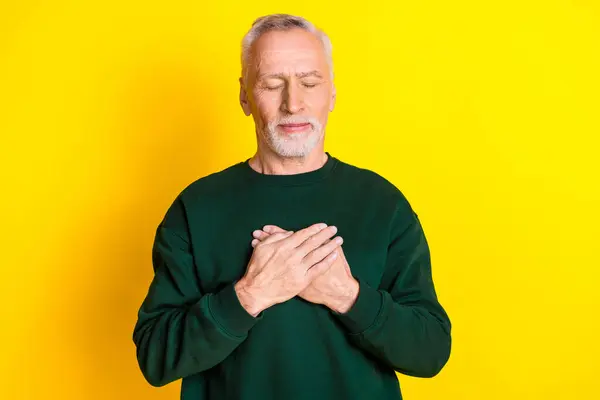 Stock image Photo portrait of lovely pensioner man touch chest heart health dressed stylish green garment isolated on yellow color background.