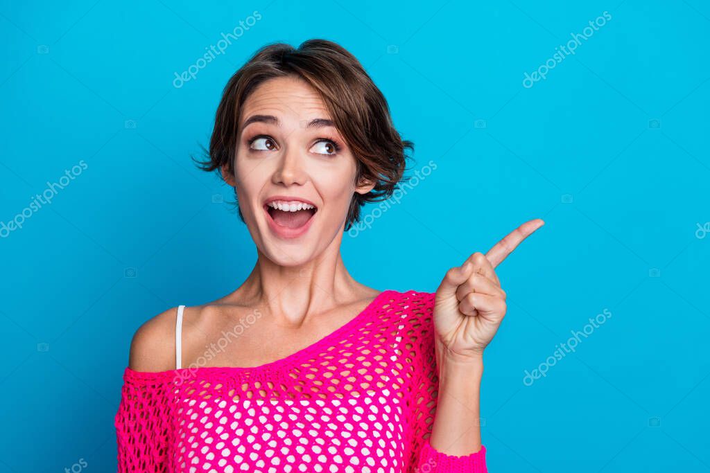 Photo of excited funky lady dressed knitted pink shirt open mouth pointing finger looking empty space isolated blue color background.