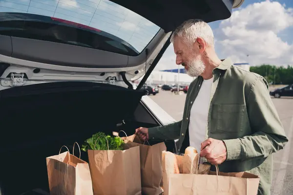 stock image Photo of attractive funny retired guy wear khaki shirt delivering bargains automobile outdoors urban city street.