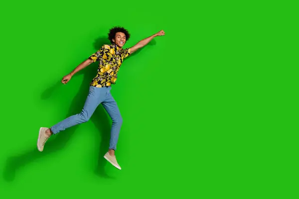 stock image Photo of optimistic positive glad man wear trendy summer print clothes fly air empty space isolated on green color background.