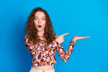 Photo portrait of lovely young lady shocked point hold empty space dressed stylish colorful garment isolated on blue color background. clipart