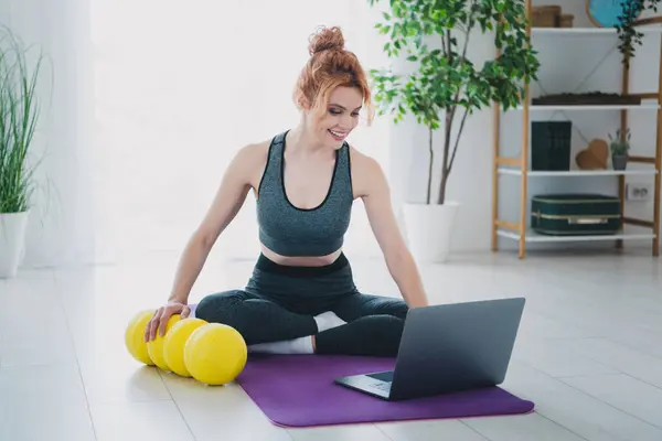 stock image Photo of attractive young woman wearing activewear showing physical exercises with fitness roller warm up indoors.