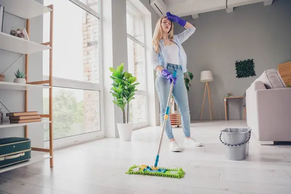 stock image Photo of tired upset young lady wear blue shirt mopping floors feeling overworked indoors room home house.