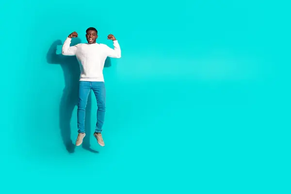 stock image Full length photo of handsome young guy jump flexing show muscles dressed stylish white garment isolated on cyan color background.