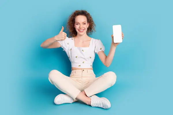 stock image Full length photo of lovely young lady sit floor gadget qr code thumb up dressed stylish white garment isolated on blue color background.