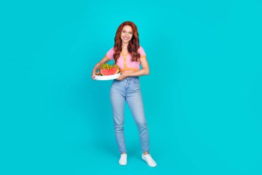 Full size photo of pretty young girl hold fruits tray wear trendy pink outfit isolated on aquamarine color background. clipart