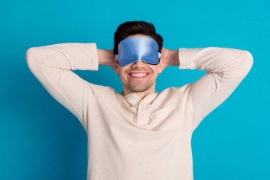 Photo of young man lying sleep hands behind head eyes covered mask dressed pajama sleepover good night isolated on blue color background. clipart