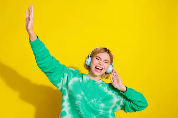 stock image Photo of adorable lovely girl wear tie dye sweatshirt singing listen songs earphones empty space isolated yellow color background.