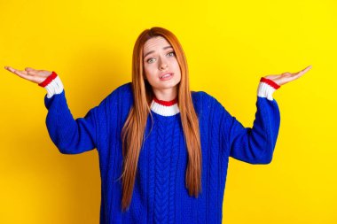 Photo portrait of attractive young woman shrug shoulders confused dressed stylish blue knitwear clothes isolated on yellow color background. clipart