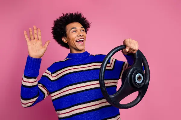 stock image Photo of nice guy with wavy hair dressed knitwear sweater hold steering wheel look empty space say hi isolated on pink color background.