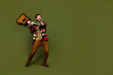 Photo of crazy angry mad man wear stylish clothes smash guitar empty space isolated on khaki color background. clipart