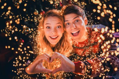 Photo of pretty young couple show heart symbol dressed christmas garment tradition atmosphere decor house indoors room. clipart