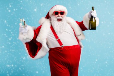 Photo of retired old man grey beard funky hold bottle full glass golden wine drink having fun open mouth wear santa x-mas costume suspender sunglass cap isolated blue color background clipart