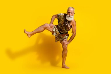 Full length photo of handsome cool neanderthal guy wear leoprad skin dancing rituals emtpy space isolated yellow color background. clipart