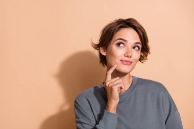 Photo portrait of attractive young woman look thoughtful empty space dressed stylish gray clothes isolated on beige color background. clipart