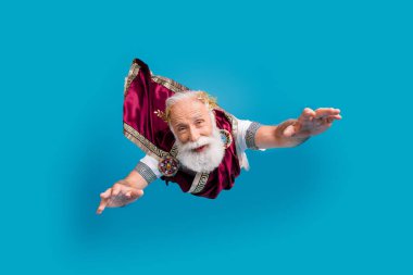 Photo of cheerful positive funny man wear ancient crown costume flight air isolated on blue color background. clipart