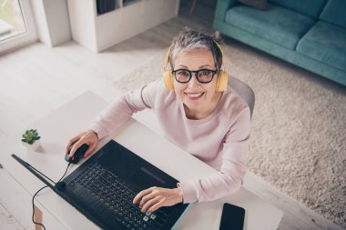 Top view photo of adorable sweet lady wear pink sweatshirt headphones playing modern device indoors room home house. clipart