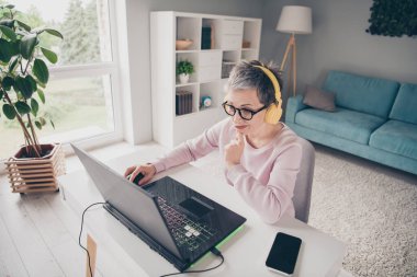 Photo of pretty cheerful lady wear pink sweatshirt headphones working modern device indoors room home house. clipart