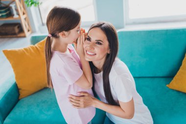 Photo of happy lovely mother with daughter together tell secret indoors cozy living room. clipart