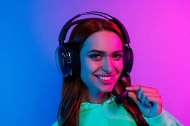 Photo of cheerful pretty lady dressed sweatshirt earphones talking microphone empty space isolated neon pink color background. clipart