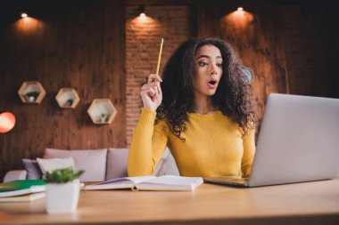 Young female student in a bright sweater studying at home, engaged with her laptop. The cozy setting and natural light create a conducive learning atmosphere. clipart