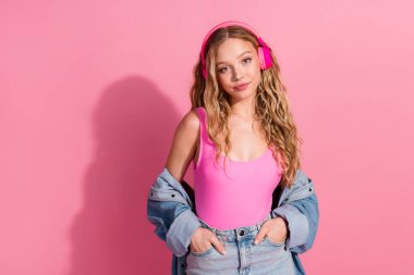 A fashionable young woman in trendy denim and vibrant headphones exudes charm and joy, set against a lively pink backdrop, capturing a youthful and stylish vibe. clipart