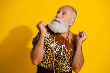 Photo of ancient aged caveman terrified look empty space wear leopard skin clothes isolated on yellow color background. clipart