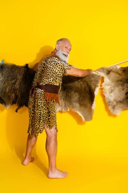 Vertical full length photo of strong paleolitic human wear leopard skin hanging rope animal fur emtpy space isolated yellow color background. clipart