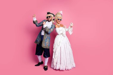 Young man and woman dressed as historic royalty enjoying playful moments in themed costumes with a bright pink backdrop enhancing the retro style atmosphere clipart