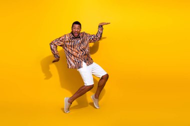 Energetic young man wears trendy tiger print shirt, white shorts, and showcases lively dance moves. Bright yellow background emphasizes his fashionable and playful style. clipart